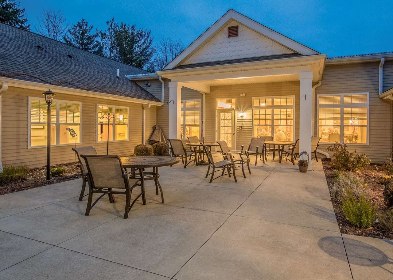The covered entrance and patio at dusk, with outdoor tables and chairs